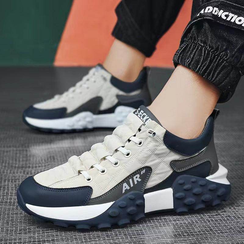 Sneakers with a mix of white, navy, and gray colors on a textured surface.