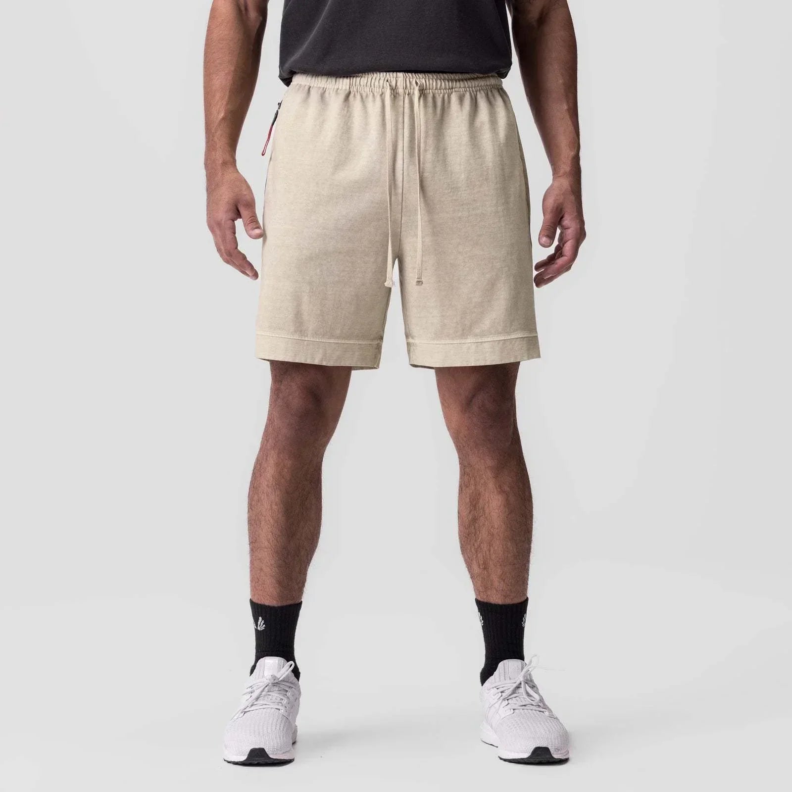 Person wearing beige shorts on a white background