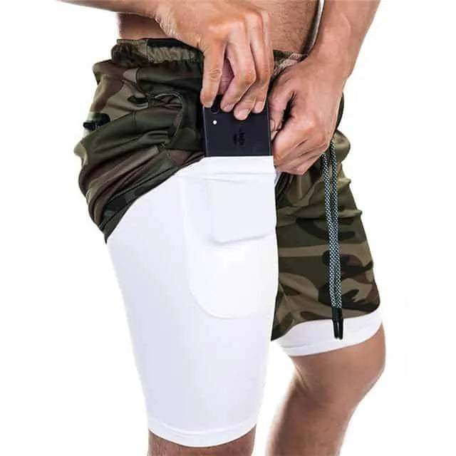 Person wearing camouflage shorts over white leggings, holding a phone.