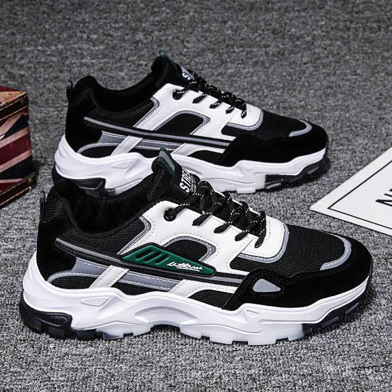 Black and white sneakers with green accents on a gray surface