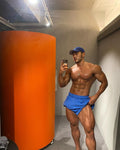 Muscular man taking a mirror selfie in a room with an orange cylindrical object.