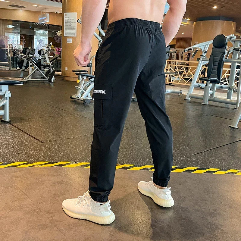 Person wearing black sweatpants with a brand logo in a gym setting