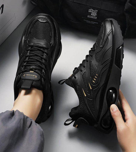 Black sneakers being worn with a gray background